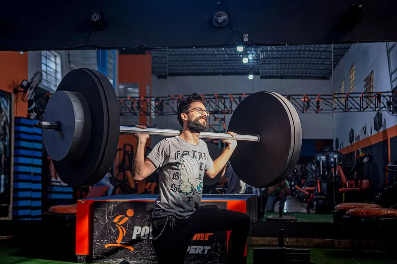 Persona levantando peso en un gimnasio con luz baja